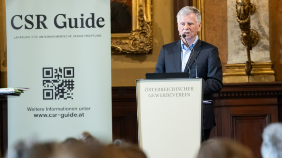 Michael Fembek, graue Haare, dunkler Anzug, bei der Präsentation des CSR-Guide